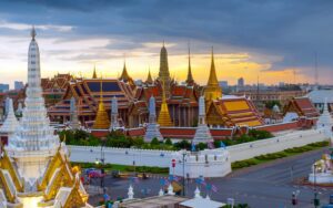 Vue panoramique du Wat Phra Kaew (Temple du Bouddha d'Émeraude) à Bangkok, avec ses toits dorés étincelants et son architecture majestueuse au coucher du soleil